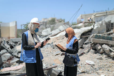UNRWA engineers with building rubble behind